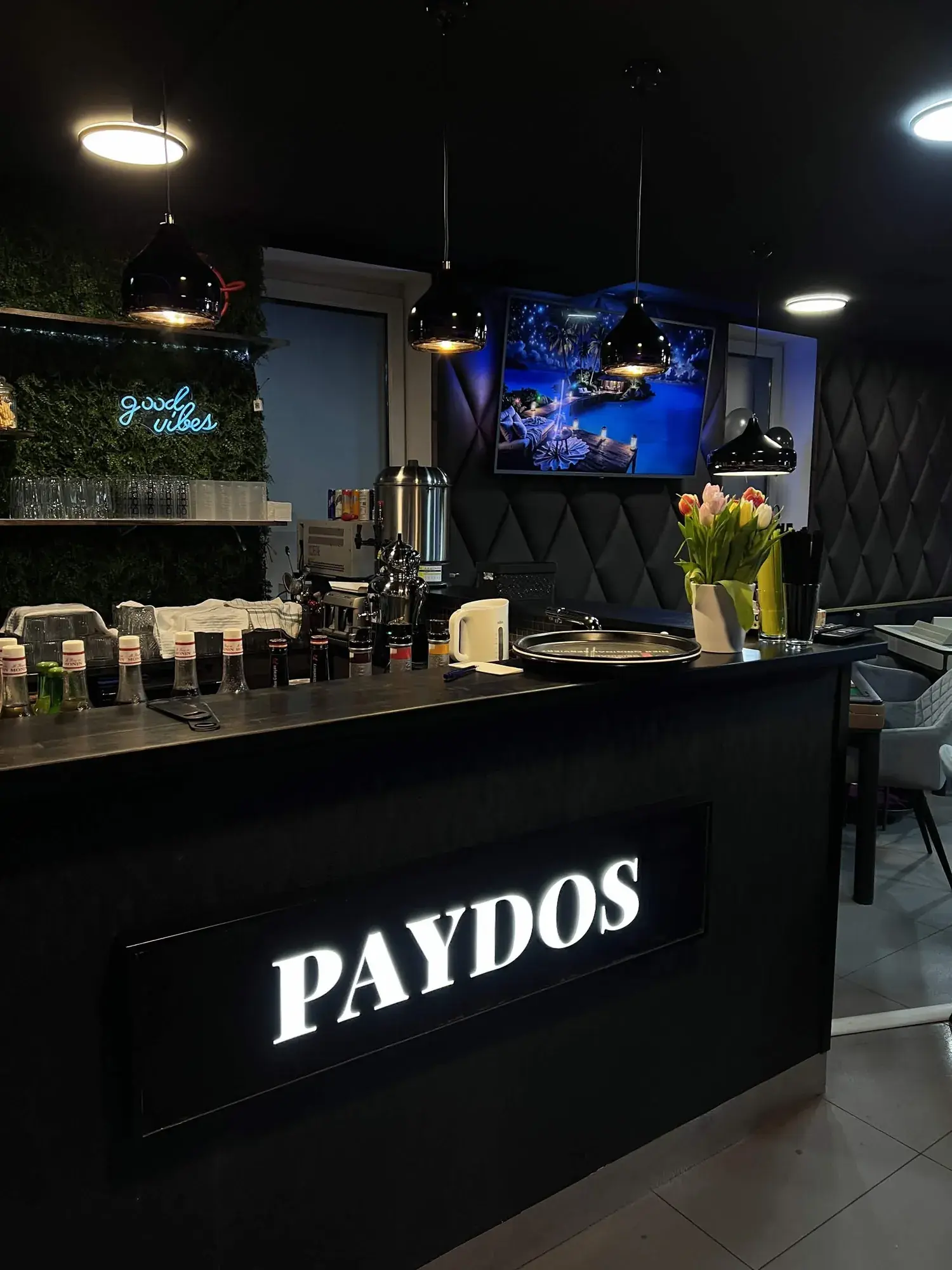 Beleuchtetes Paydos-Schild an der Bar